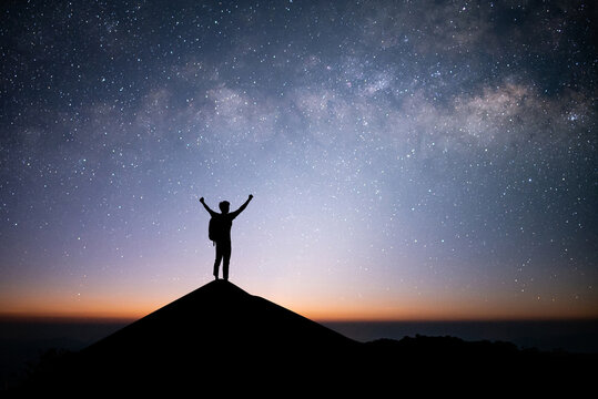 Young traveler and backpacker standing and open arm watched the star and milky way alone on top of the mountain. He enjoyed traveling and was successful when he reached the summit.