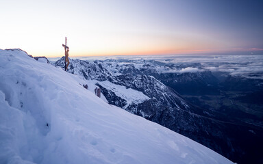 Naklejka na ściany i meble Peak with a wooden cross Watzmann mountain at sun rise in winter with a lot of snow, Berchtesgaden national park, Bavaria, Germany