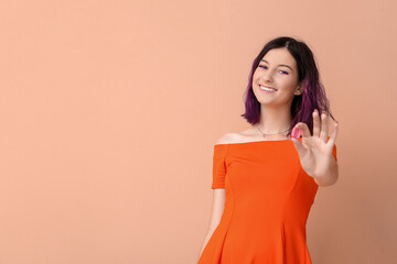 Young woman with pink chewing gum on beige background