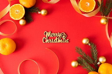 Naklejka premium The inscription merry christmas on a red background is decorated with Christmas decorations, ribbons, tangerines and coniferous branches. Christmas card.