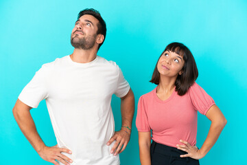 Fototapeta na wymiar Young couple isolated on blue background posing with arms at hip and laughing