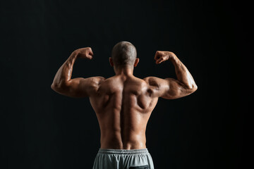 Fototapeta na wymiar Male bodybuilder on dark background, back view