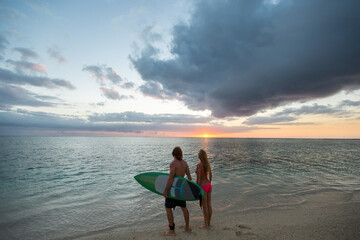 Obraz premium Man and a Woman with Surf Boards at Sunset