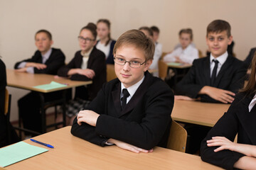 Happy schoolchildren sit at a desk in the classroom