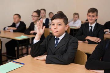Happy schoolchildren sit at a desk in the classroom