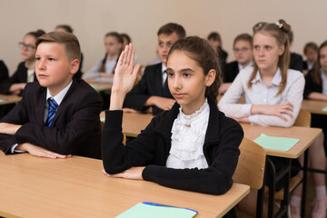 Happy schoolchildren sit at a desk in the classroom