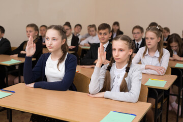 Happy schoolchildren sit at a desk in the classroom