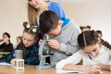 Students using science beakers and a microscope at the elementary school