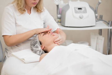 Obraz premium Woman beautician makes a professional massage to a young girl. Beauty treatments for skin care in the SAP salon. Health facial masseur. Relax cosmetology procedure