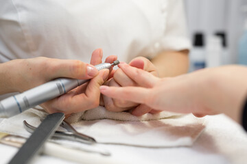 Close-up of manicurist doing hardware manicure to a young beautiful girl in the spa salon. Hardware manicure. Concept of body care