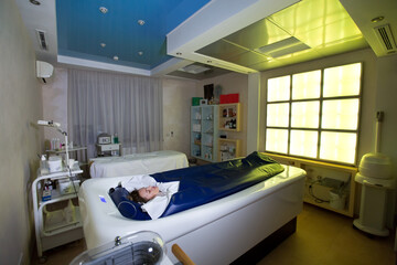 Young happy girl enjoys the procedure of wrapping and hydro massage in the Spa salon. Professional modern cosmetology. Body care. The process of the hydromassage bath in the cosmetology clinic.