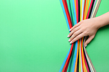 Female hand with many different shoe laces on color background, closeup