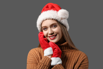 Beautiful woman in Santa hat and with mittens on dark background