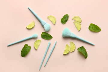 Stylish makeup brushes with lime and mint on color background