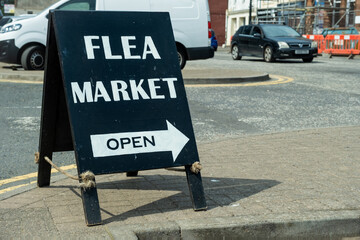 Black Flea Market sign stating that it is open and pointing the direction