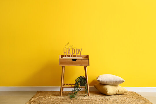Wooden bedside table with decor near yellow wall