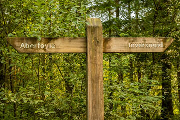 An old wooden sign pointing the trail directions to Aberfoyle and Inversnaid