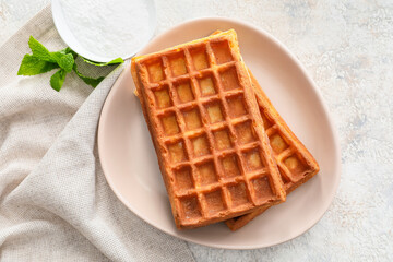 Plate with tasty Belgian waffles and mint on light background