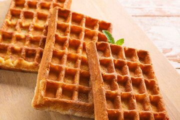 Board with yummy Belgian waffles on table, closeup