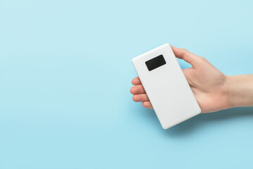Woman holding modern power bank on blue background