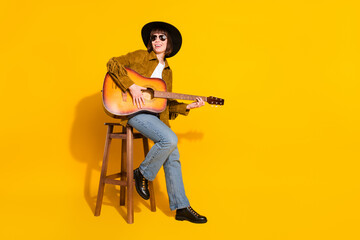 Photo of charming cute woman dressed cowboy clothes spectacles cap singing playing guitar empty space isolated yellow color background