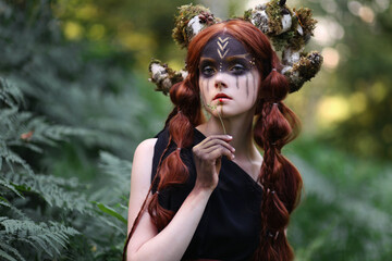 Beautiful red haired girl with braided hair and dark faceart with mossy horns among fern. Faitytale portrait of faun in dark forest - obrazy, fototapety, plakaty