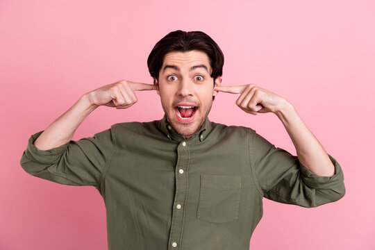 Photo of excited funky annoyed man fingers cover ears scream wear khaki shirt isolated pink color background