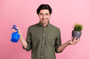 Photo of young happy positive cheerful man hold hands plant pulverizer water isolated on pink color background