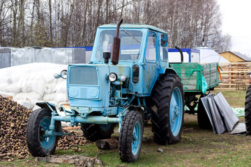 Old blue tractor stands in the village.