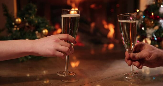 Hands holding and clinking glasses of champagne on christmas  decorated and  flames  background. Celebration, holidays and drinks concept 