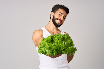 cheerful man in a white t-shirt lettuce leaves healthy food