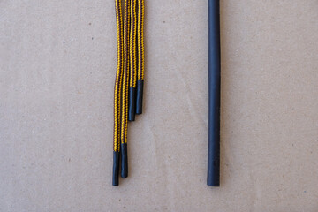 Heat shrink tubing and yellow shoelaces on gray paper. Repair of shabby laces at home.