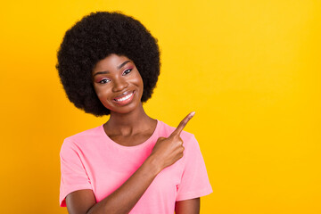 Photo of young african girl happy positive smile point finger empty space ad advice isolated over yellow color background