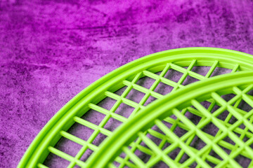 two tops of plastic badminton tennis rackets are bright green on a velvet violet background