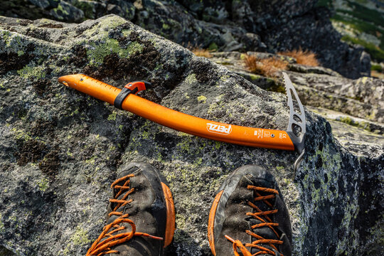 The Petzl Ride ice axe and Scarpa Mescalito approach boots on a granite boulder at the summit during your autumn mountain hike.