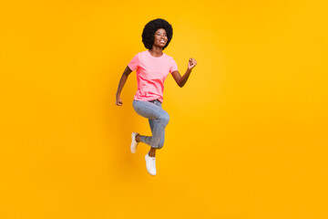 Fototapeta na wymiar Full body photo of excited millennial lady jump run wear pink t-shirt jeans isolated on yellow color background