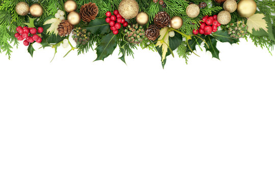 Christmas background border with gold bauble decorations, holly, mistletoe, cedar and ivy on white background. Flat lay, top view, copy space.
