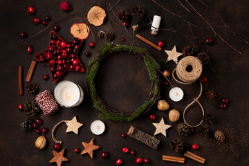 Yule winter solstice concept. Present box, decorations, green tree branches, red berries, burning candles on dark wooden background.
