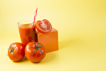 Tomato juice and tomatoes on a yellow background. Tomato juice with a red tube and red tomatoes on a colored background copy space