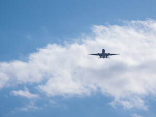青空と雲を背景にこちらへ向かって飛んでくる飛行機