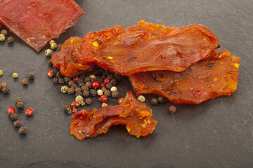 Jerky with spices on a black stone cutting board,