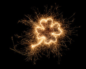 golden bright sparkler four leaf clover shape happiness shaped symbol isolated dark black...