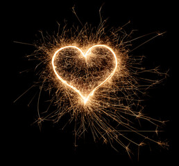 golden bright sparkler heart shape love shaped symbol isolated dark black background. silvester new year birthday wedding and celebration design pattern