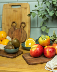 Auswahl an Obst auf Frettchen, in verschiedenen Schalen und Tellern auf Holzuntergrund mit Fliesenspiegel. Gesunde, vitaminreiche, vegane Ernährung, ethisch nachhaltiger Lebensstil, umweltfreundlich, 