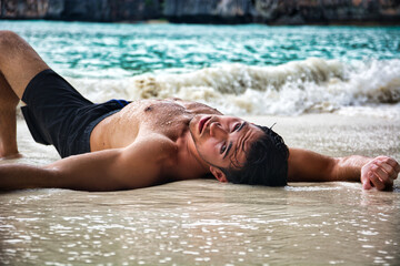 Shirtless young man on the beach lying on sand - Powered by Adobe
