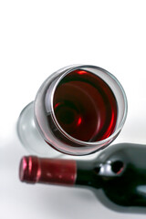 Glass and bottle of red wine on a light background.