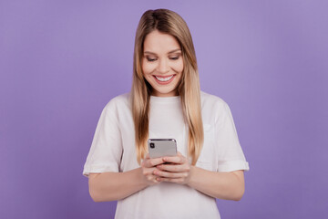 Naklejka premium Photo of blogger influencer lady hold telephone texting friends wear casual t-shirt on violet background