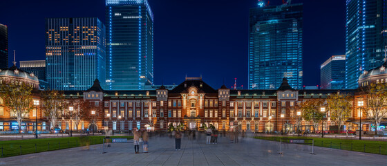 Facade of Tokyo station and business buildings at night.