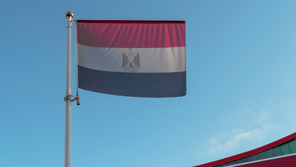 National flag of Egypt on a flagpole in front of blue sky with sun rays and lens flare. Diplomacy concept.