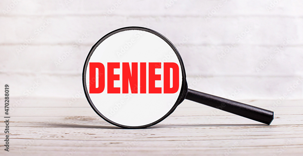Poster the magnifying glass stands vertically on a light background with the text denied